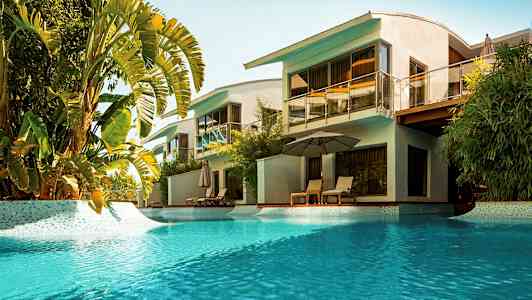 Billede af en tropisk pool ved moderne villaer. (AI-genereret tekst)
