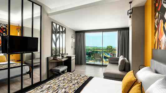 Moderne hotelværelse med seng, sofa og udsigt til balkon med panoramaudsigt. (AI-genereret tekst)