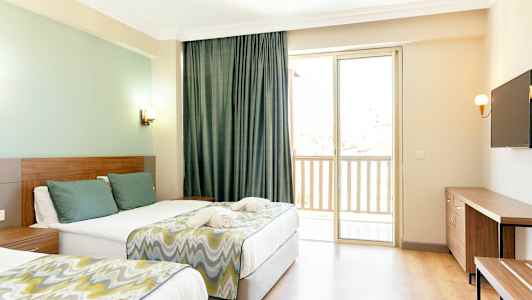 Et hotelværelse med to senge, en TV på væggen og et vindue med balkon. (AI-genereret tekst)