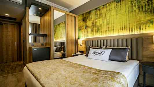 Et moderne hotelværelse med en dobbeltseng, dekorativ pude og farverig vægkunst. (AI-genereret tekst)