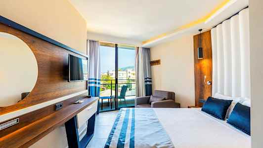 Hotelværelse med seng, lænestol, TV og altan med udsigt. (AI-genereret tekst)