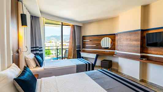 Hotelværelse med to senge og udsigt gennem glasdøre mod bjerge. (AI-genereret tekst)