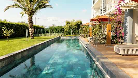 En lang smal pool omgivet af grønne områder og en moderne bolig. (AI-genereret tekst)