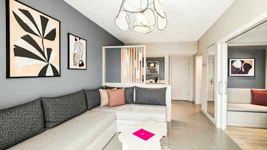 En moderne stue med grå vægge, en hjørnesofa og kunst på væggen. (AI-genereret tekst)