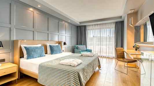 Hotelværelse med en dobbeltseng, to lænestole og et skrivebord. (AI-genereret tekst)