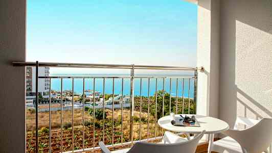 Udsigt fra en altan med to moderne stole, et bord og havet i baggrunden. (AI-genereret tekst)