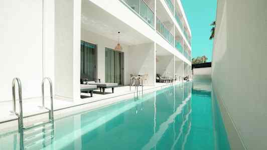 Billede af en lang pool ved siden af en moderne hvid bygning med private siddepladser. (AI-genereret tekst)