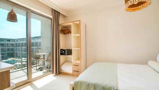 Hotelværelse med seng, garderobe og altan med udsigt til en pool. (AI-genereret tekst)