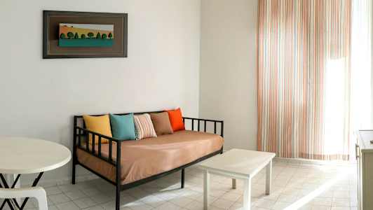 En stue med en sofa, puder i forskellige farver, et lille bord og et billede på væggen. (AI-genereret tekst)