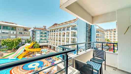 Altan med udsigt over hotelbygninger og en pool med vandrutsjebane. (AI-genereret tekst)