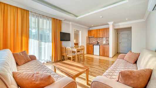 Et opholdsområde med to sofaer, et sofabord, et spisebord og et åbent køkken. (AI-genereret tekst)