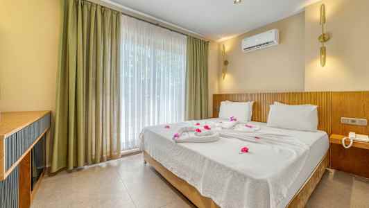 Hotelværelse med en dobbeltseng redt med hvide lagner og dekoreret med blomster. (AI-genereret tekst)