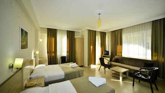 Et hotelværelse med to enkeltsenge, en sofa, bord og stole. (AI-genereret tekst)