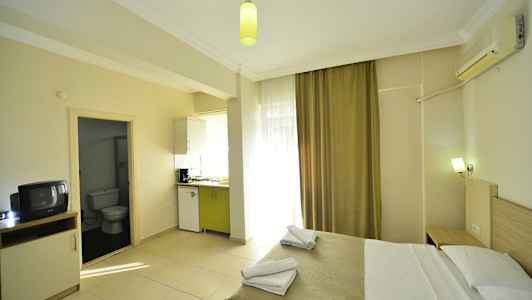 Et hotelværelse med en seng, tekøkken og indgang til badeværelse. (AI-genereret tekst)