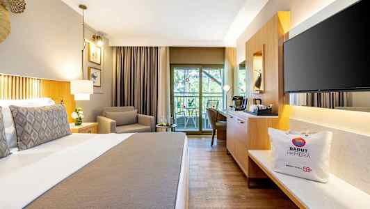 Et hotelværelse med en komfortabel seng, en lænestol, en siddegruppe ved balkonen og moderne møbler. (AI-genereret tekst)