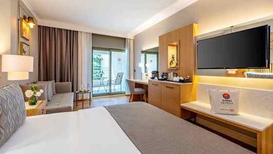 Et velindrettet hotelværelse med en dobbeltseng, siddegruppe, skrivebord og en balkon. (AI-genereret tekst)