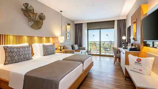 Hotelværelse med to enkeltsenge, dekorativ belysning og udsigt til en balkon med møbler. (AI-genereret tekst)