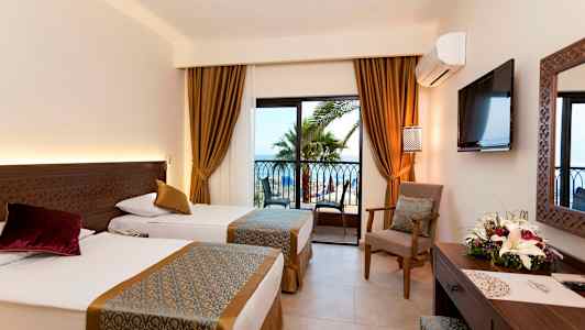 Hotelværelse med to enkeltsenge, vindue med udsigt til palmer og hav. (AI-genereret tekst)