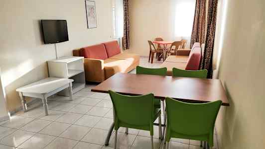 Et opholdsområde med sofaer, et spisebord med stole og et vægmonteret tv. (AI-genereret tekst)