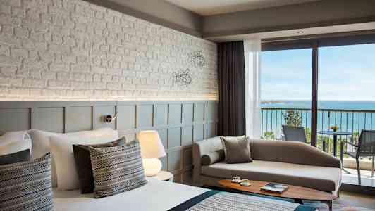 Billede af et moderne hotelværelse med havudsigt fra en balkon. (AI-genereret tekst)