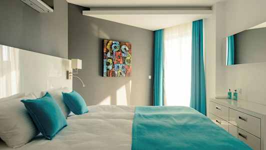 Moderne soveværelse med dobbeltseng, turkise detaljer og lyse møbler. (AI-genereret tekst)