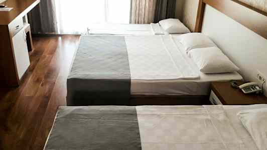 Hotelværelse med to senge og et skrivebord. (AI-genereret tekst)