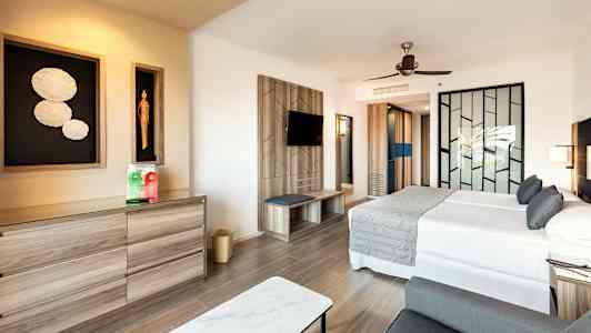 Moderne hotelværelse med dobbeltseng, siddeområde og kunst på væggen. (AI-genereret tekst)