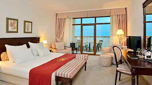 Et hotelværelse med dobbeltseng, siddeområde og altan med havudsigt. (AI-genereret tekst)