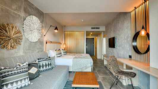 Et hotelværelse med to senge, en sofa og indretningsdetaljer. (AI-genereret tekst)