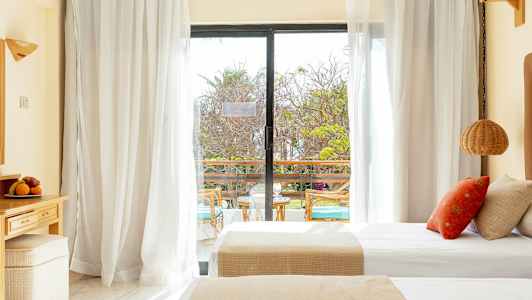 Et hotelværelse med dobbeltsenge og en glasdør, der fører ud til en altan. (AI-genereret tekst)