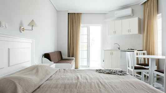 Et overblik over et hotelværelse med en seng, sofa, køkken og spisebord. (AI-genereret tekst)