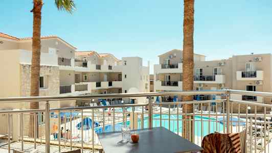 Hotelbygning med altaner og pool, set fra en terrasse. (AI-genereret tekst)