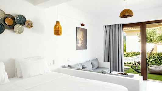 Et hotelværelse med lys indretning og åbning til en terrasse med grøn beplantning. (AI-genereret tekst)