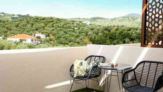 En altan med udsigt over et grønt landskab og huse med røde tage. (AI-genereret tekst)