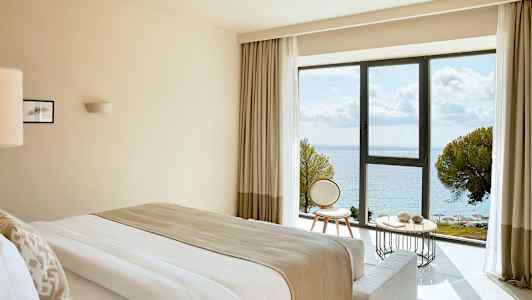 Hotelværelse med havudsigt gennem et stort vindue. (AI-genereret tekst)