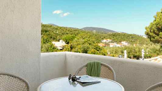 Udsigt fra en balkon med et bord, solbriller og avis, samt grønne omgivelser. (AI-genereret tekst)