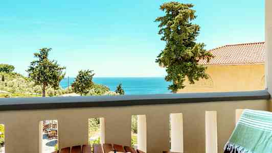 Udsigt fra en balkon med havudsigt og træer i baggrunden. (AI-genereret tekst)