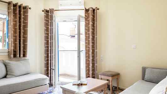 Billede af en lys stue med to sofaer, et sofabord og gardiner foran en altandør. (AI-genereret tekst)