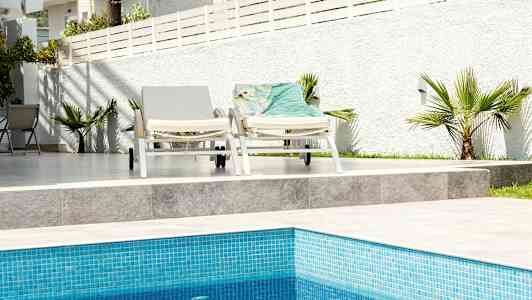 To liggestole ved en pool med hvid baggrundsgrænse. (AI-genereret tekst)