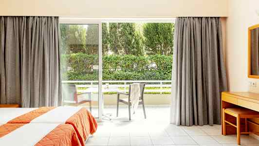 Hotelværelse med to enkeltsenge og stor vinduesdør, der fører ud til en altan. (AI-genereret tekst)