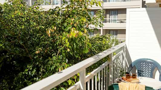 Billede af en altan med bord, stol og grønt område i forgrunden. (AI-genereret tekst)