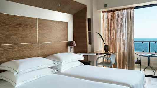 Hotelværelse med to enkeltsenge, skrivebord og havudsigt. (AI-genereret tekst)