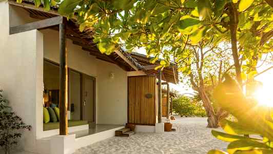 Bungalower på stranden omgivet af grønne områder og oplyst af solskin. (AI-genereret tekst)