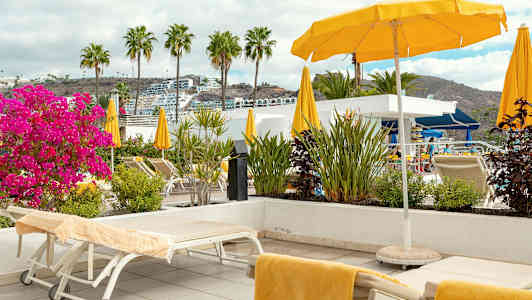 Liggestole og parasoller på en terrasse med udsigt. (AI-genereret tekst)