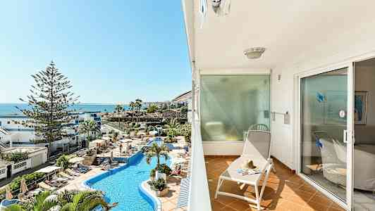 Altan med liggestol og udsigt over poolområdet og havet. (AI-genereret tekst)