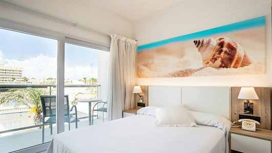 Hotelværelse med balkon og udsigt, seng og dekoration med strandmotiv. (AI-genereret tekst)