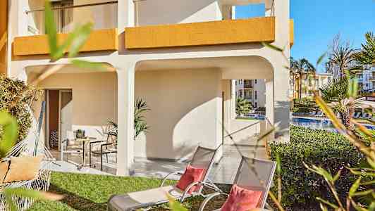 Udendørsområde med græsplæne, liggestole og parasol ved et hotel. (AI-genereret tekst)