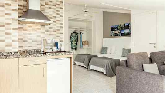 Et åbent hotelværelse med et tekøkken, senge og siddepladser. (AI-genereret tekst)