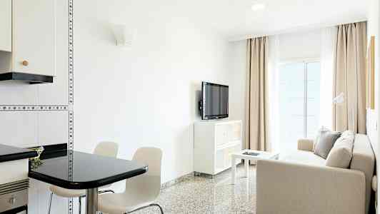 En lys stue med en sofa, bord, tv og spiseområde. (AI-genereret tekst)