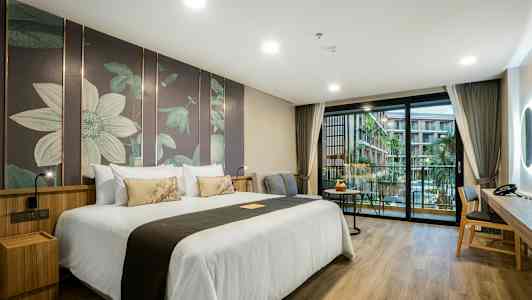 Hotelværelse med en stor dobbeltseng, moderne indretning og en balkon med udsigt over en pool og bygninger. (AI-genereret tekst)